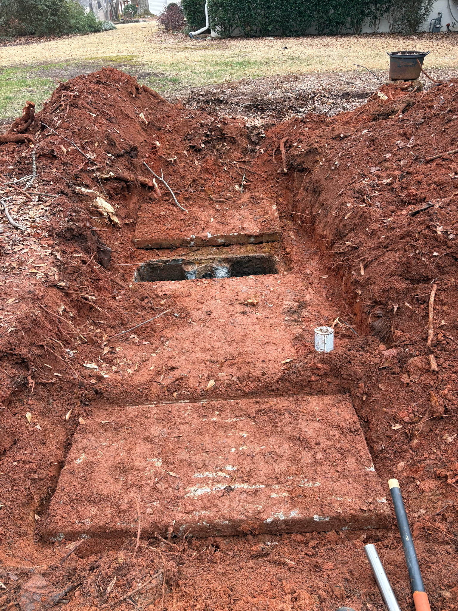 Excavated old concrete septic tank uncovered in red Georgia clay by Sanders Septic Loganville