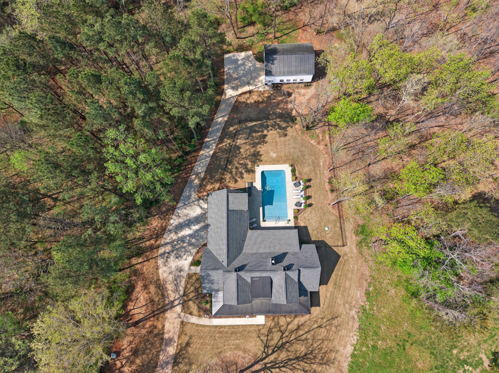 Aerial drone view of 4746 Bentley Road Monroe GA — in-ground saltwater pool, detached workshop garage, and full 2-acre lot from above
