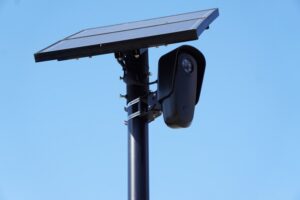 Flock Safety license plate reader camera mounted on a pole beside a suburban Georgia road at dusk