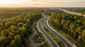 Aerial view of a new parkway with landscaped medians and walking trails cutting through Georgia pine forest near Highway 316 in eastern Gwinnett County